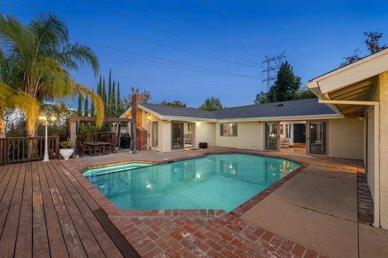 Plano a media noche, una casa color blanco y tejado gris y piscina al frente